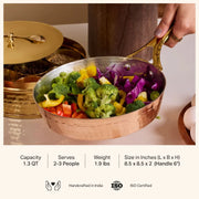 Copper frypan with brass handle, filled with colorful vegetables, held by a hand. A spice box is in the background.