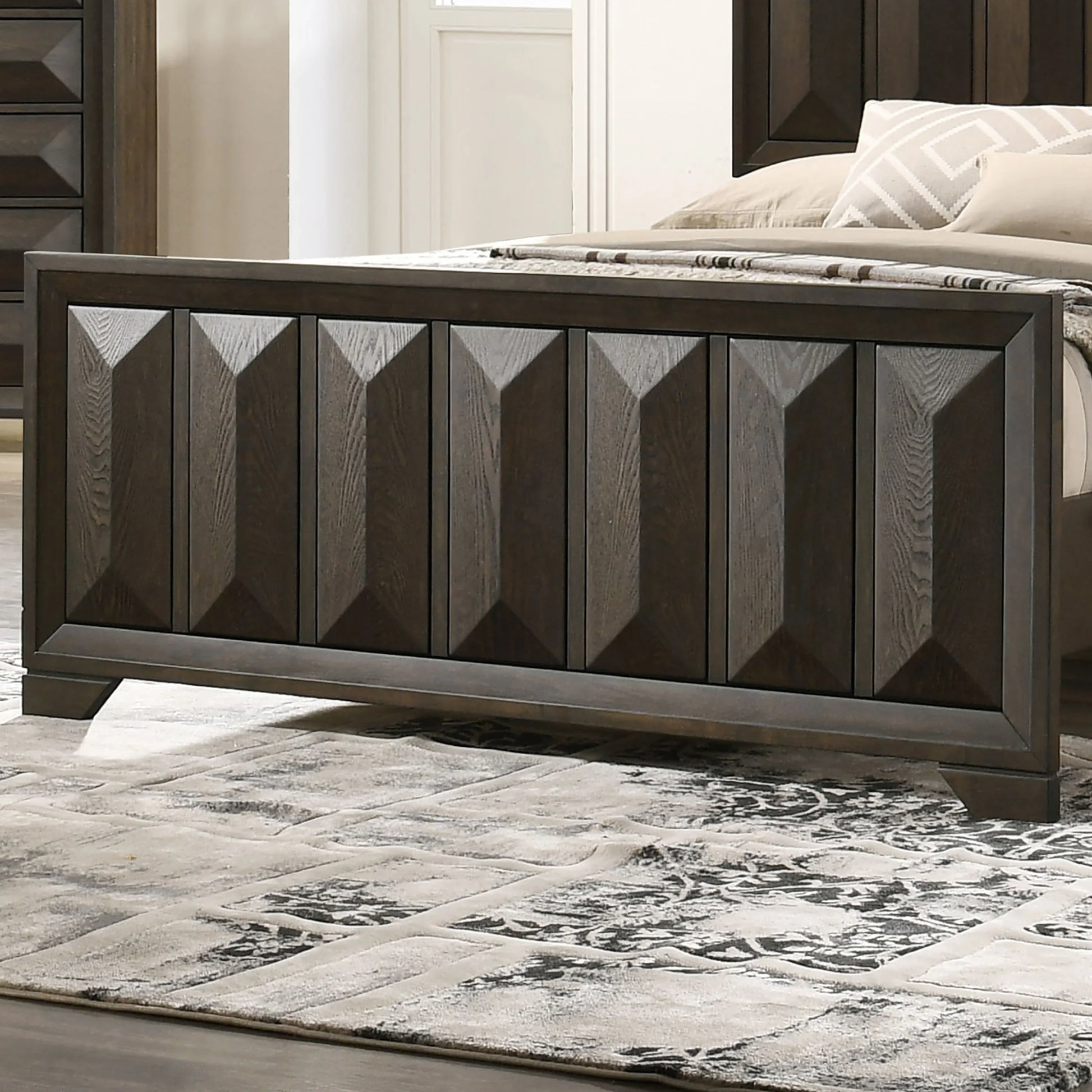 Close-up of the espresso king bed footboard highlighting the architectural vertical faceted panels and wood grain texture.