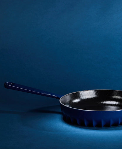 A lifestyle view of the FIREUP Oxford Blue skillet on a kitchen counter, highlighting its iconic design and versatility for serving directly to the table.