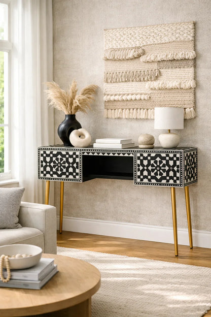 Black and white bone inlay console desk styled in a boho living room with pampas grass woven wall art and gold legs

