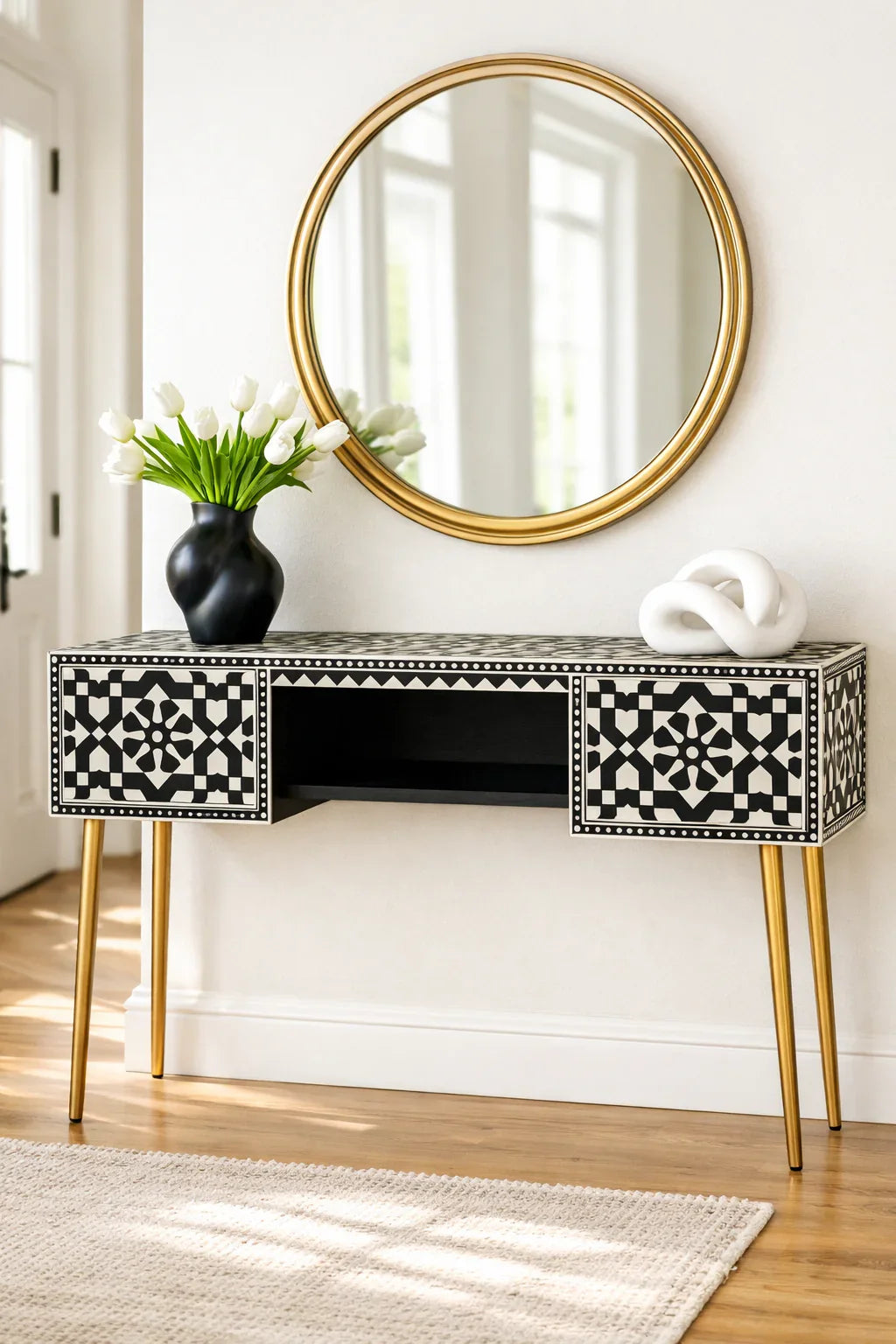 Black and white bone inlay console desk styled in a modern entryway with gold mirror white tulips and sculptural décor

