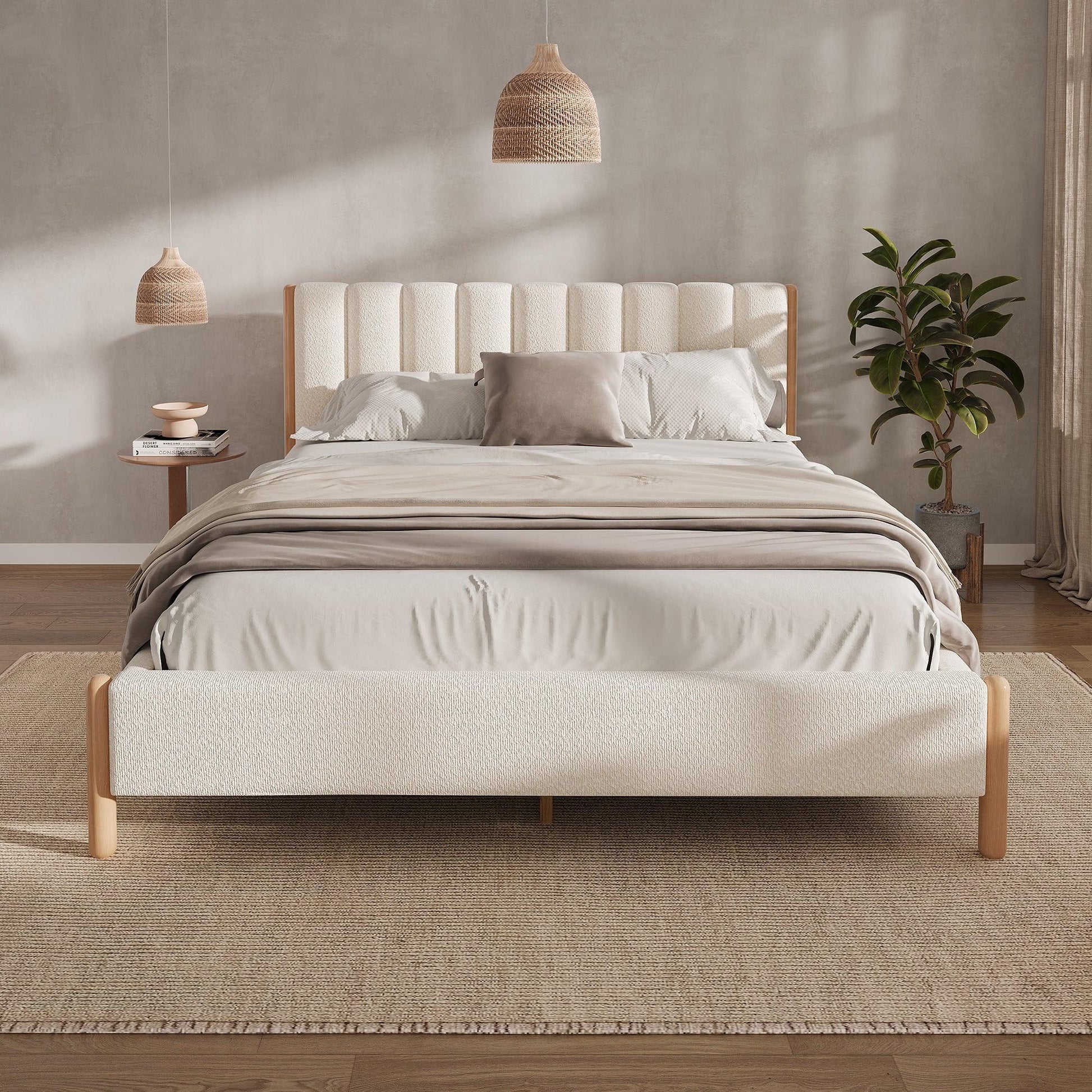 White bouclé queen bed frame with vertical panel headboard and natural rubberwood legs styled in warm neutral bedroom with rattan pendants and fiddle leaf fig

