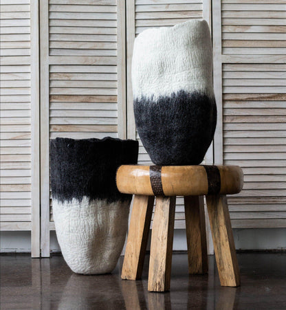 Two black and white ombré wool floor vases styled on rustic wood stool and dark floor against whitewashed shutter backdrop

