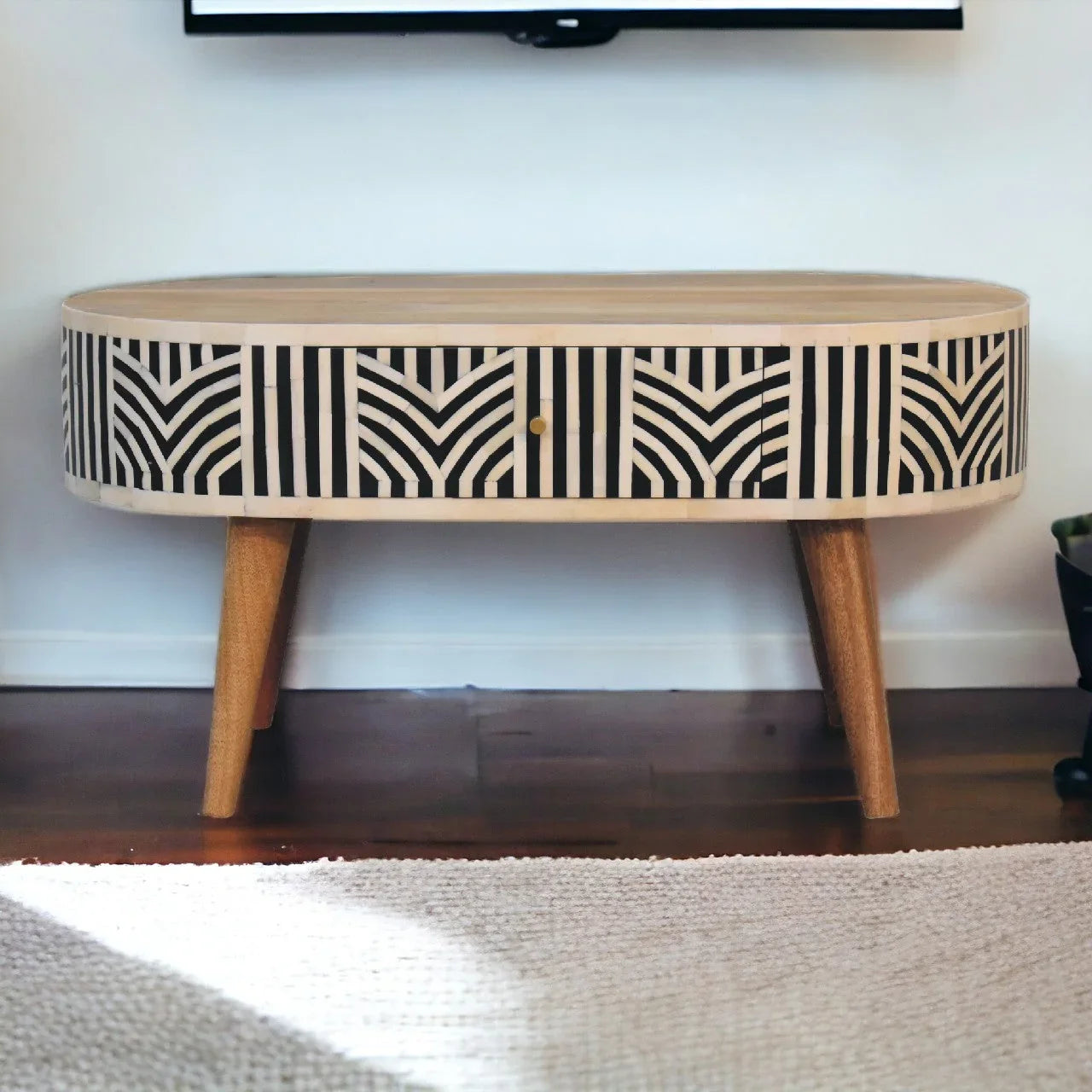 Edessa bone inlay coffee table front view showing geometric black and white inlay pattern across drawer front with tapered mango wood legs on hardwood floor

