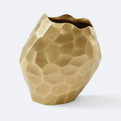Modern gold faceted aluminum vase with hammered geometric texture on a light gray background

