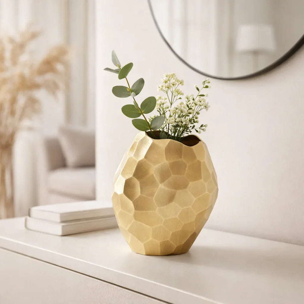 Gold faceted aluminum vase styled with eucalyptus and white florals on a white console table in a modern entryway

