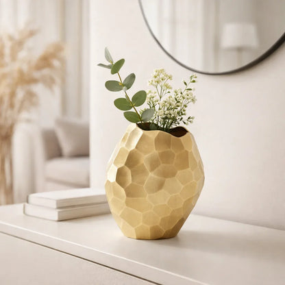 Gold faceted aluminum vase styled with eucalyptus and white florals on a white console table in a modern entryway

