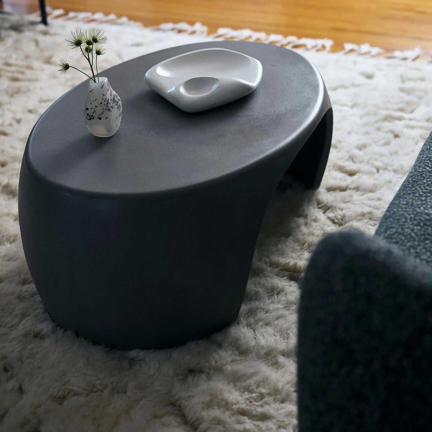 Black Micro Terrazzo Nook concrete coffee table styled with speckled ceramic vase and sculptural white dish on ivory shag rug

