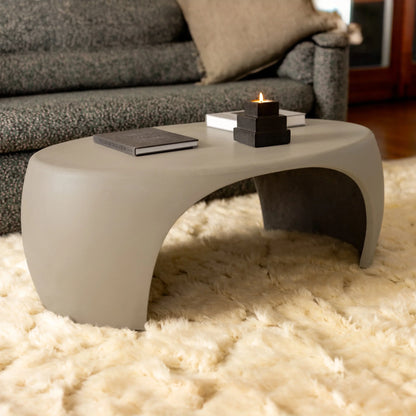 Slate Nook concrete coffee table styled with art book and tiered candle holder on ivory shag rug beside charcoal sofa

