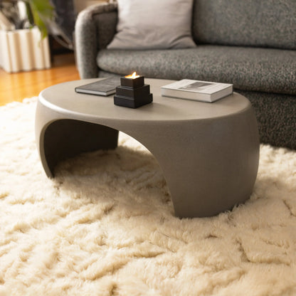 Slate Micro Terrazzo Nook concrete coffee table styled with tiered candle holder and art books on ivory shag rug beside charcoal sofa

