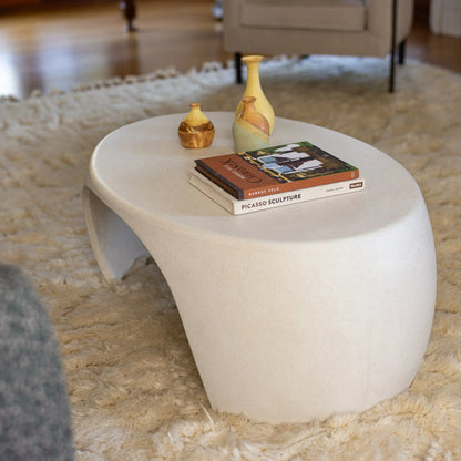 White Micro Terrazzo Nook concrete coffee table styled with gold vases and art books on ivory shag rug

