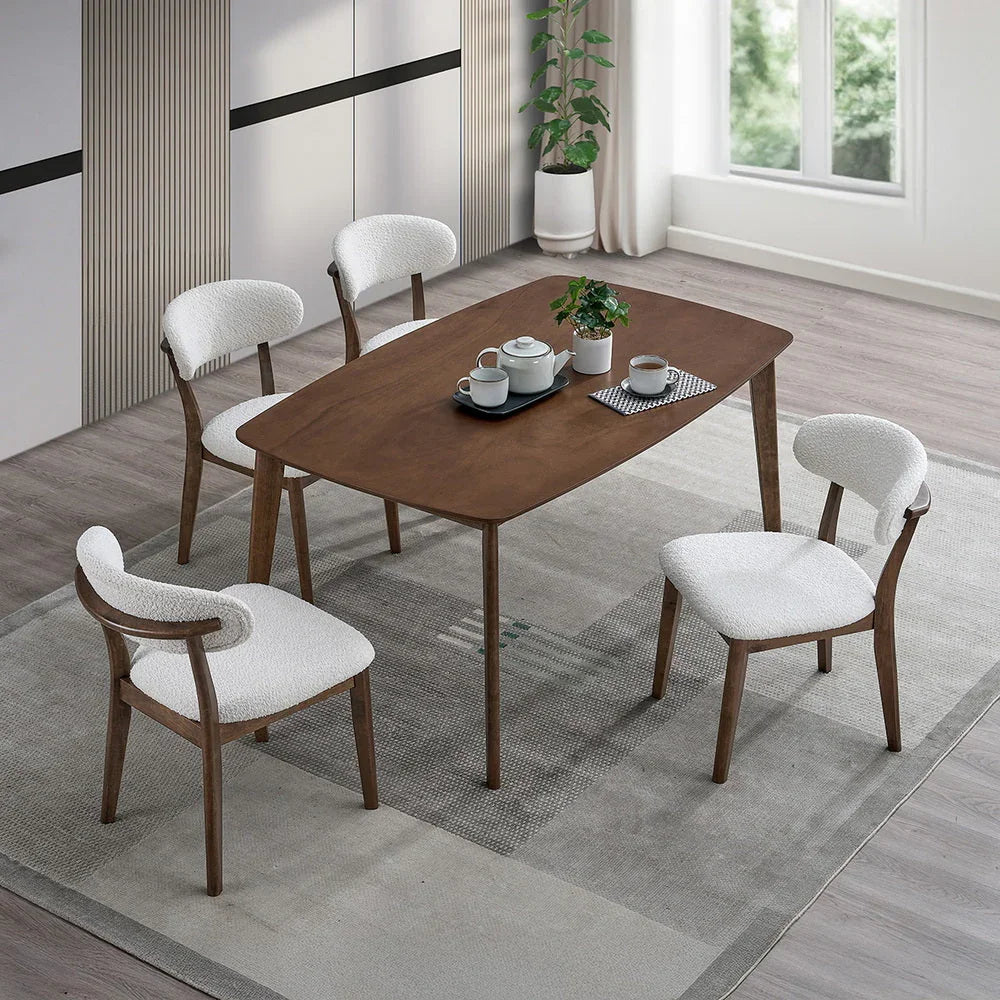 Walnut Scandinavian wood dining set with four bouclé upholstered chairs styled overhead with tea service and indoor plant on gray area rug

