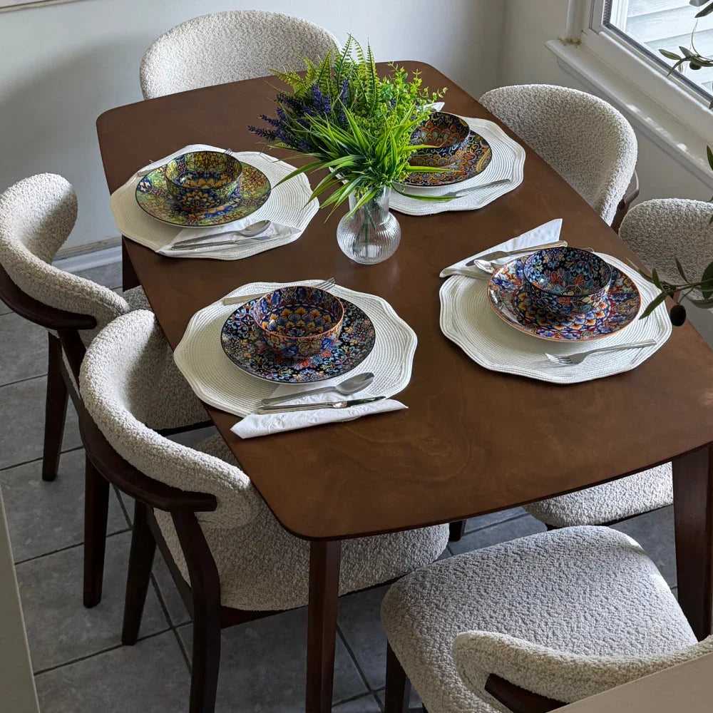 Walnut Scandinavian wood dining set styled with bouclé chairs colorful place settings woven placemats and fresh botanicals in natural light


