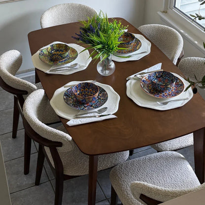 Walnut Scandinavian wood dining set styled with bouclé chairs colorful place settings woven placemats and fresh botanicals in natural light

