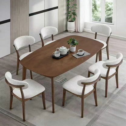 Walnut Scandinavian wood dining set with six bouclé upholstered chairs styled overhead with tea service and indoor plant on gray area rug

