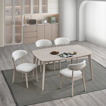 White-washed Scandinavian wood dining set with four upholstered bouclé chairs styled in a modern open-plan kitchen with light wood floors and gray rug

