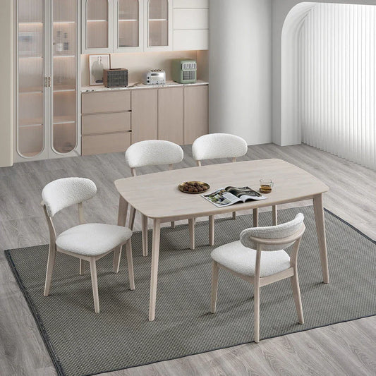 White-washed Scandinavian wood dining set with four upholstered bouclé chairs styled in a modern open-plan kitchen with light wood floors and gray rug

