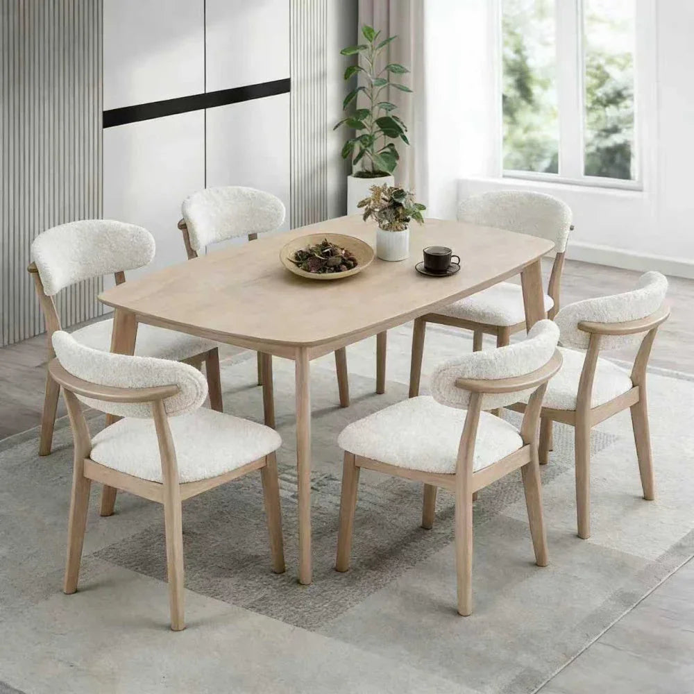 White-washed Scandinavian wood dining set with six upholstered bouclé chairs styled in a bright modern dining room with natural light and indoor plant

