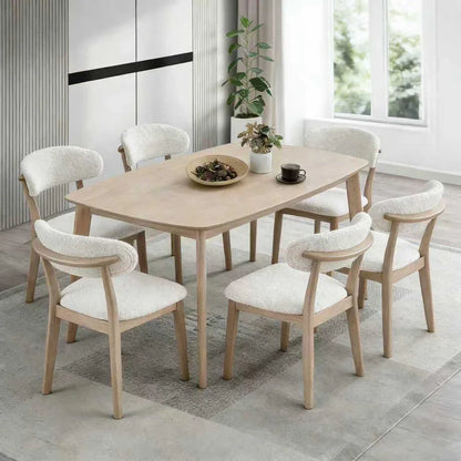 White-washed Scandinavian wood dining set with six upholstered bouclé chairs styled in a bright modern dining room with natural light and indoor plant


