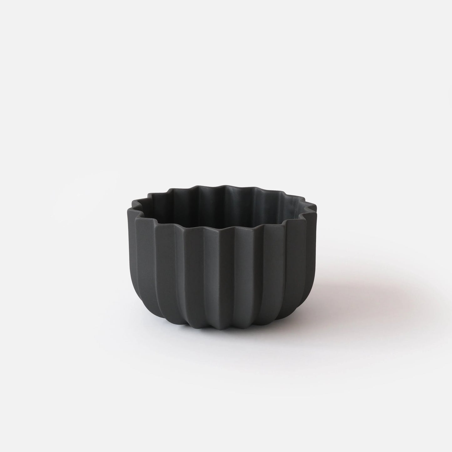 Black Wrap Planter 7 inch medium size empty on white studio background showing sculptural vertical ridge detail

