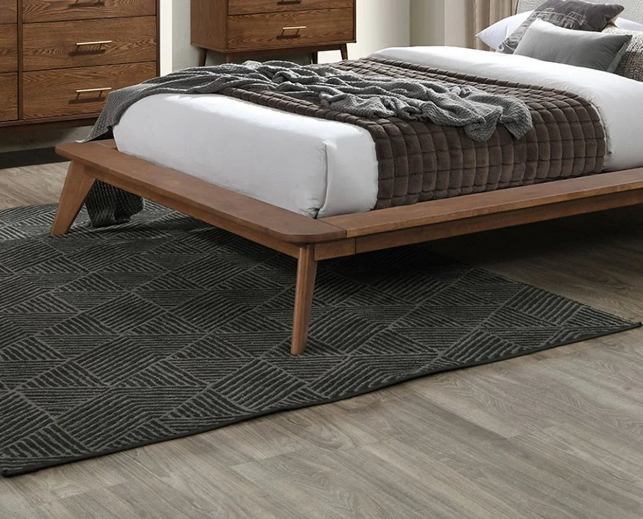 Detailed close-up of a full size upholstered bed frame showing the seamless joint craftsmanship of the low-profile walnut border and solid wood leg