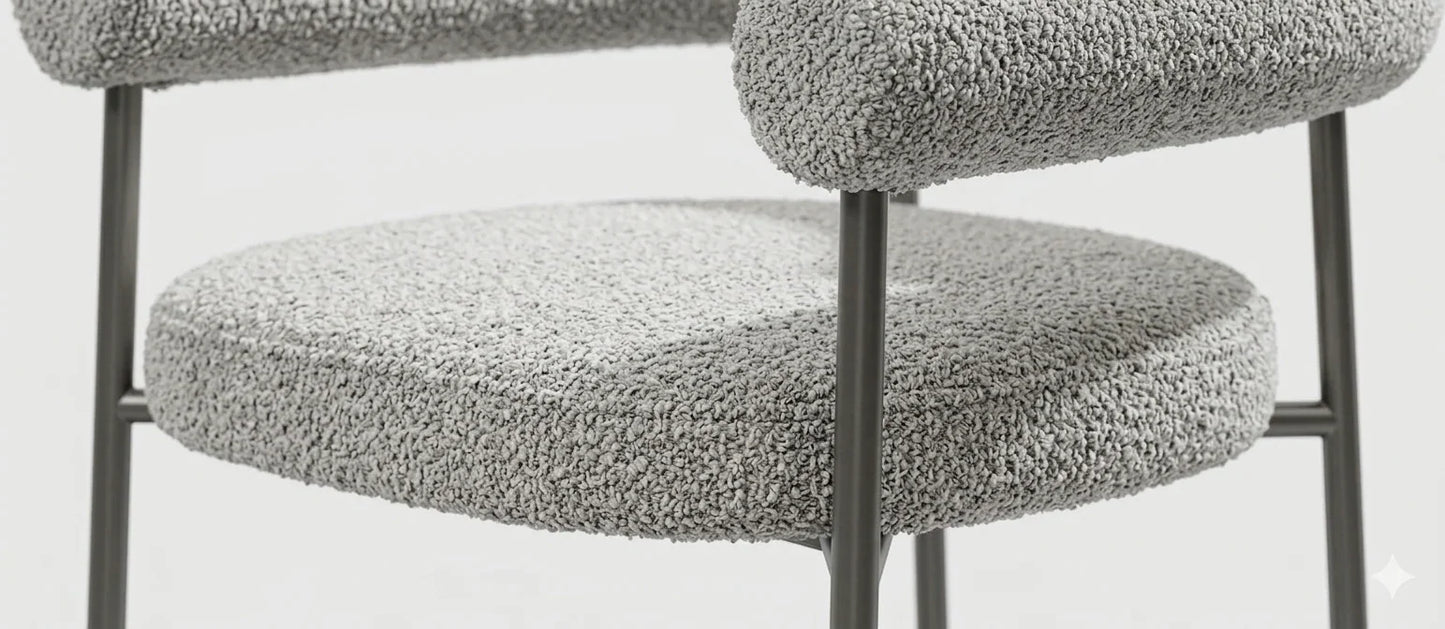 Close-up texture detail of light gray woven boucle fabric upholstery and foam cushioning on a contemporary armchair.
