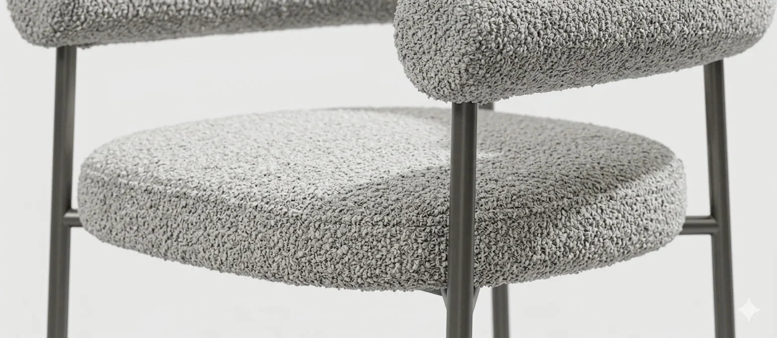 Close-up texture detail of light gray woven boucle fabric upholstery and foam cushioning on a contemporary armchair.