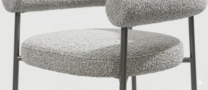 Close-up texture detail of light gray woven boucle fabric upholstery and foam cushioning on a contemporary armchair.