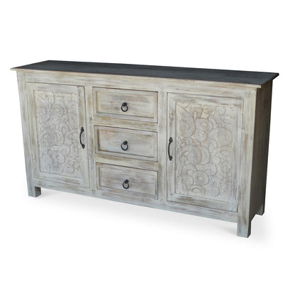 Hand carved antique sideboard angled view showing two floral carved doors three center drawers with iron ring pulls dark top surface and white antique distressed reclaimed acacia wood finish on white background