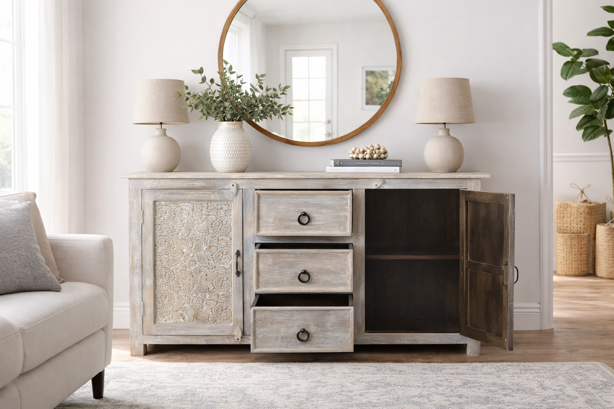 Hand carved antique sideboard with right door open showing interior shelf three pull drawers with iron ring hardware and floral carved left door panel in white antique finish