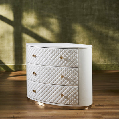 Harvard Quilted Three-Drawer Leather Chest white oval three drawers brass knobs gold base angled side view dappled light green wall hardwood floor