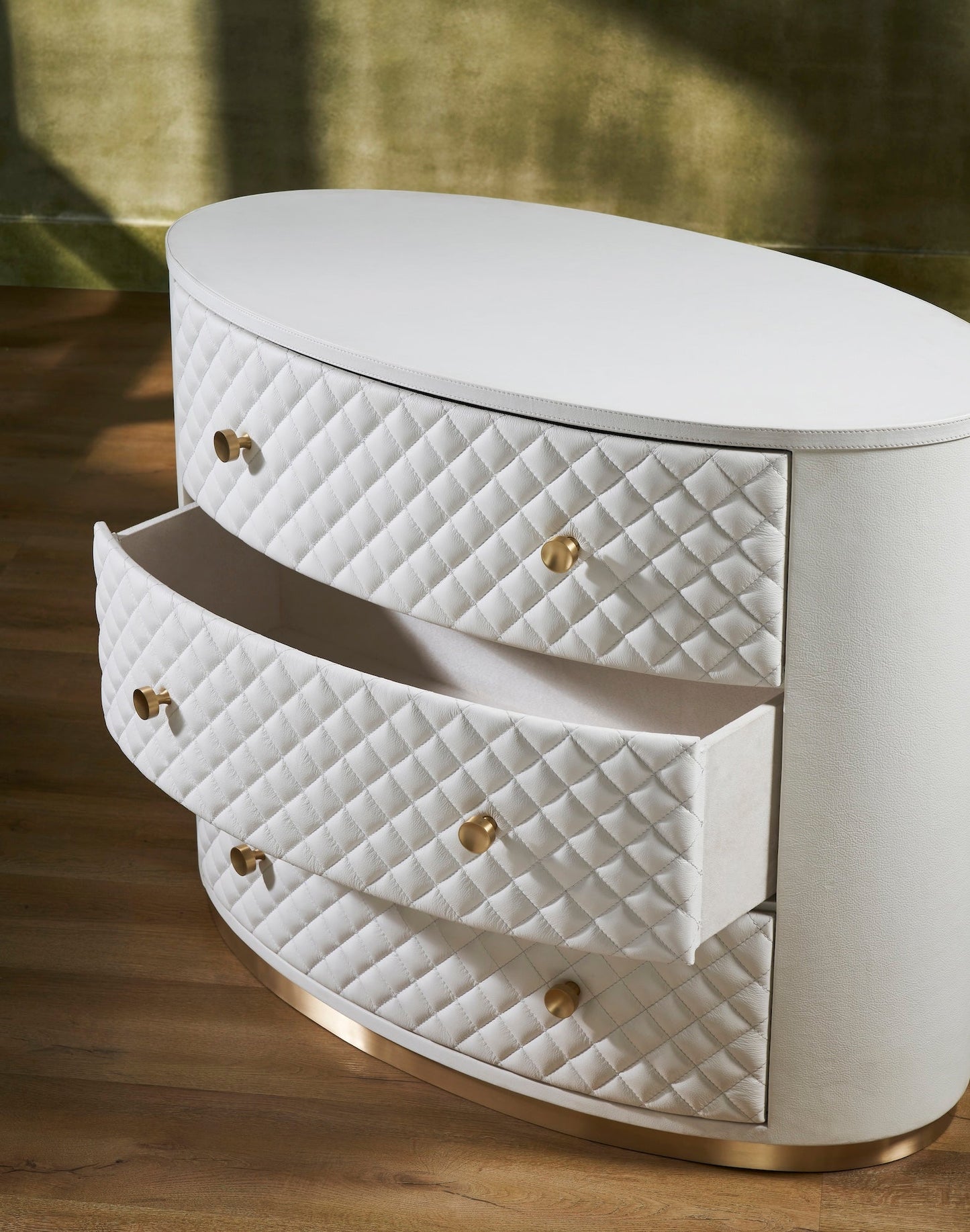 Harvard Quilted Three-Drawer Leather Chest white oval silhouette diamond-quilted drawers brass knobs gold base open drawer warm natural light