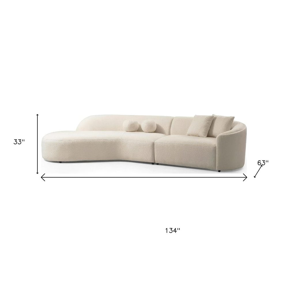 Ivory boucle curved modular sectional dimension diagram showing 134 inches wide, 33 inches high, and 63 inches deep with toss pillows on a white background