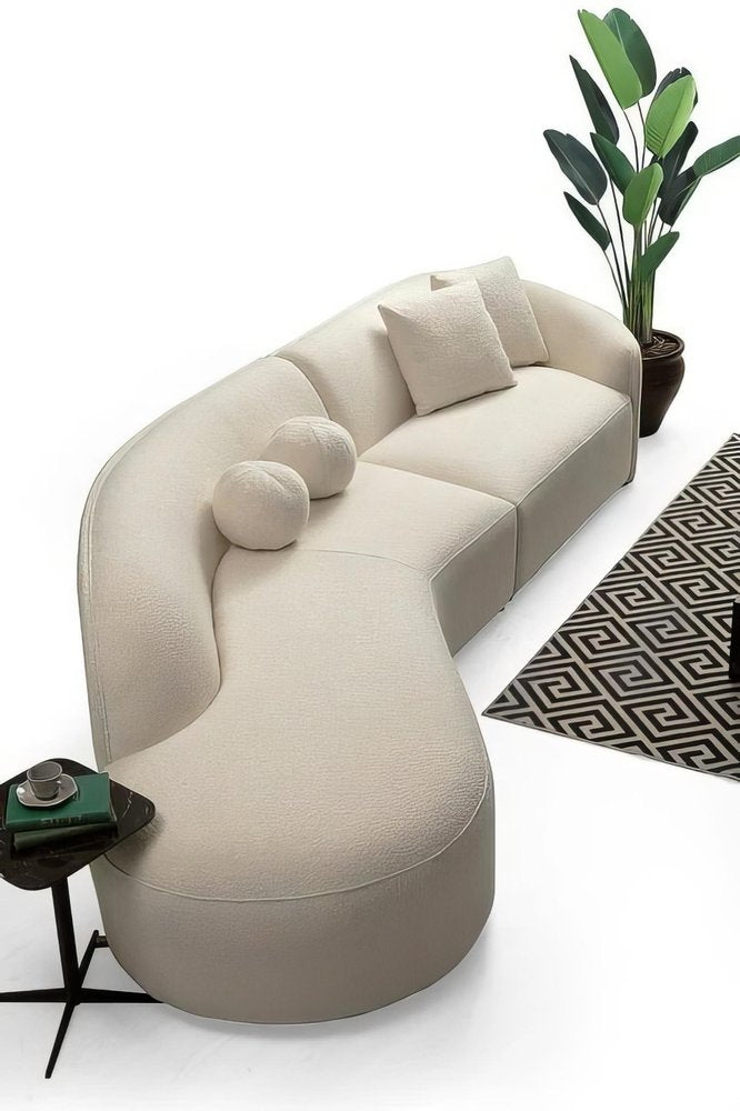 ivory-boucle-curved-modular-sectional-overhead-view-with-geometric-rug-and-plantIvory boucle curved modular sectional viewed from above with round toss pillows, geometric area rug, potted tropical plant, and small side table