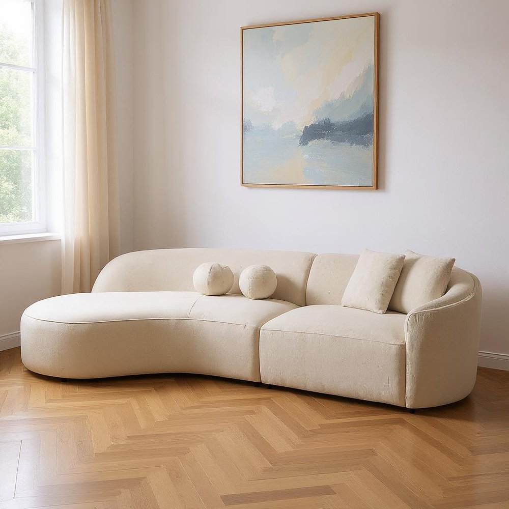 Ivory boucle curved modular sectional styled in a minimalist living room with herringbone wood floors, sheer curtains, natural light, and abstract art above