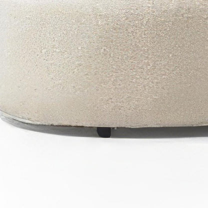 Close up of ivory boucle sectional chaise base showing looped yarn fabric texture and small dark leg on a white background