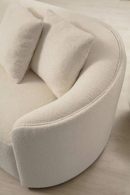 Close up of ivory boucle sectional curved back with soft textured fabric detail and two toss pillows resting against the tight back