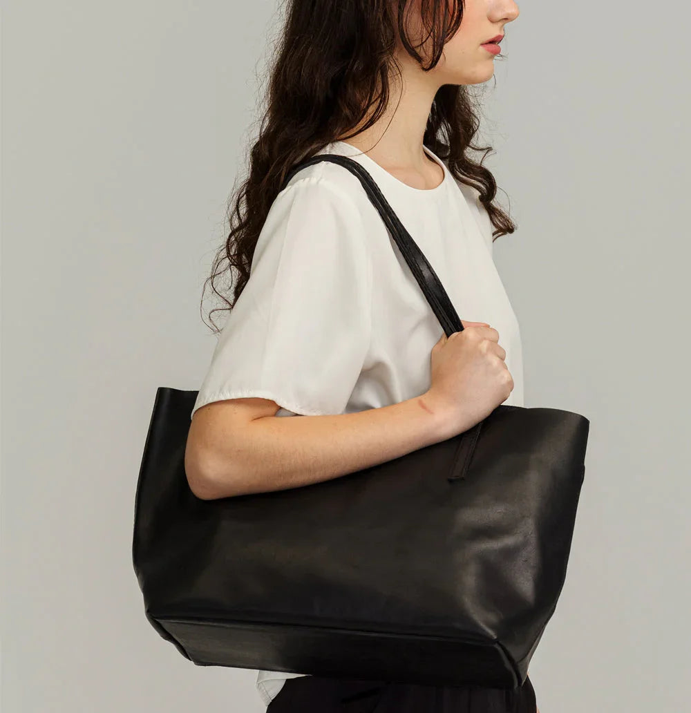 Lady Bird Carryall Black lifestyle shot woman shoulder carry natural leather long strap side profile light background