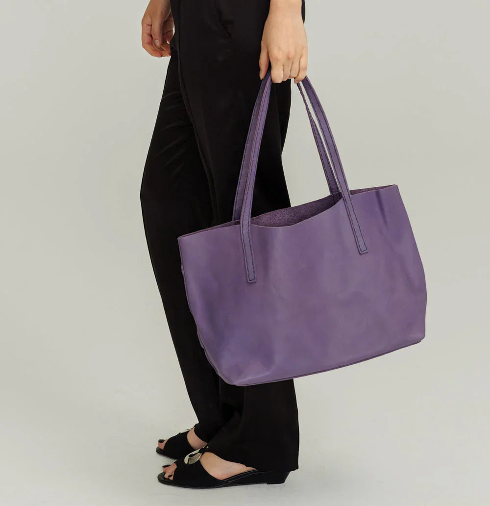 Lady Bird Carryall Wisteria lifestyle shot woman hand carry full length natural leather long straps structured silhouette grey background