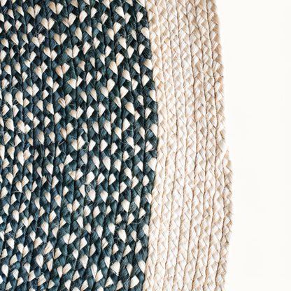 Close-up fiber detail of round sisal rug showing two-tone braid transition between charcoal black and natural cream sisal fiber bundles with visible hand-woven weave structure