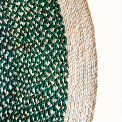 Close-up fiber detail of round sisal rug forest green variant showing two-tone braid transition between deep forest green and natural cream sisal fiber bundles with curved border edge visible