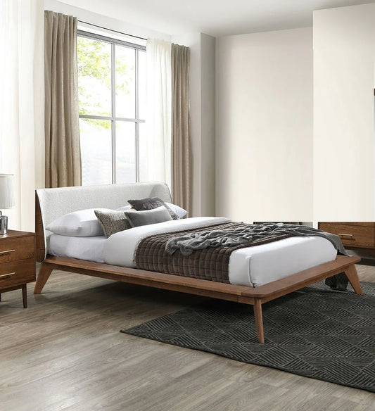 ​A mid century full bed with a beige boucle winged headboard styled in a modern bedroom alongside a patterned area rug and warm curtains