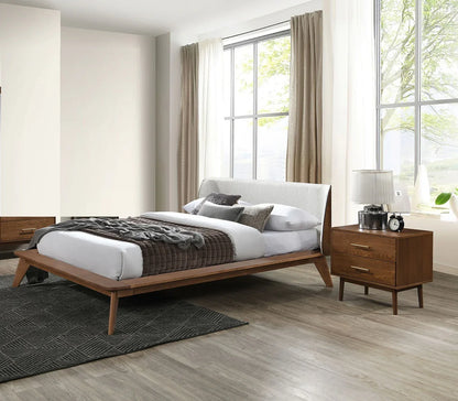 Mid-century walnut platform bed with beige boucle headboard and matching nightstand in a bright modern bedroom
