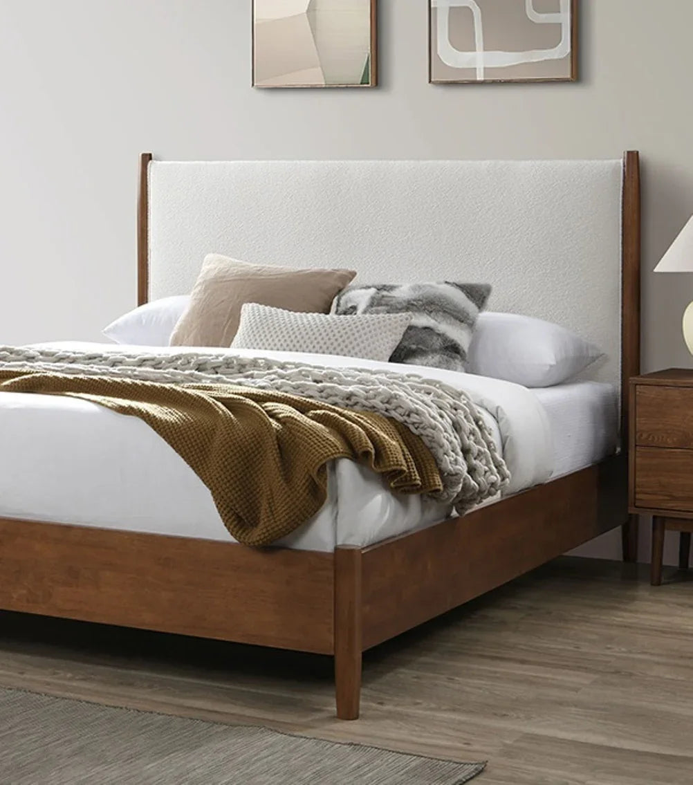 Warm walnut mid-century modern platform bed featuring tapered wooden legs, styled with cozy layered bedding and a mustard yellow textured throw blanket