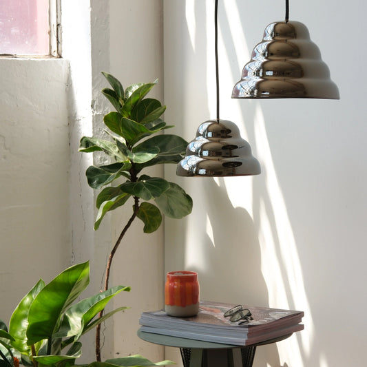 Modern ceramic pendant lights illuminating a minimalist side table styled with curated books and fresh greenery decorative elements