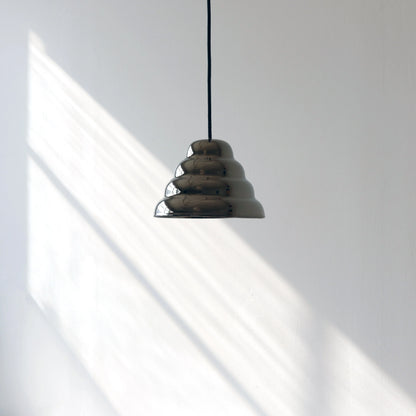 Modern ceramic pendant light casting architectural shadows on a clean minimalist white wall with natural sunlight streaming across the surface