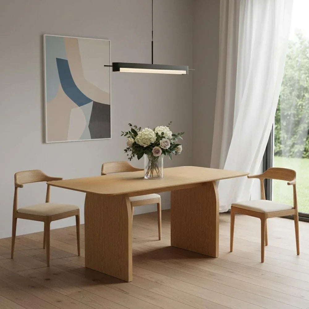 Premium sixty-six inch natural solid oak double pedestal dining table styled with three modern wooden wishbone chairs under a linear pendant light fixture