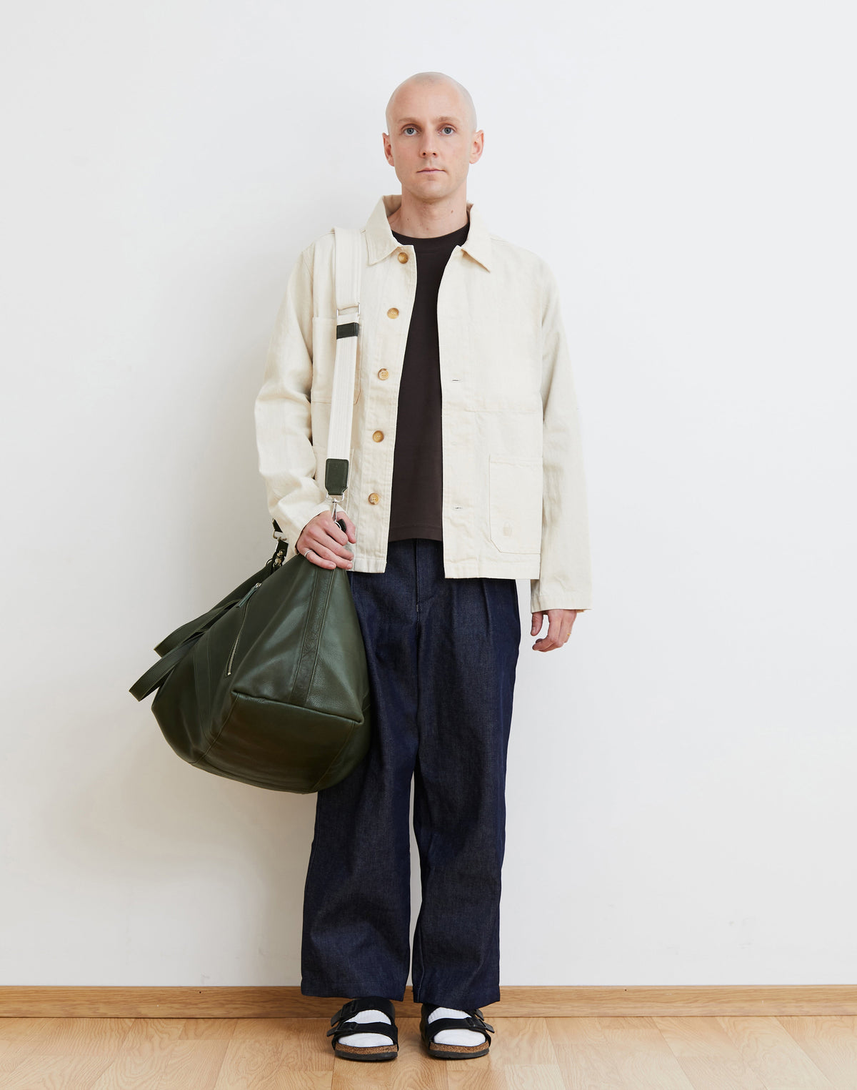 Model wearing the Malbec leather weekender in Green over one shoulder, showing how the bag rests at the hip.
