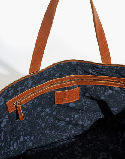 Interior of the Malbec weekender showing dark patterned lining, a leather-trimmed zip pocket, and a stitched leather label