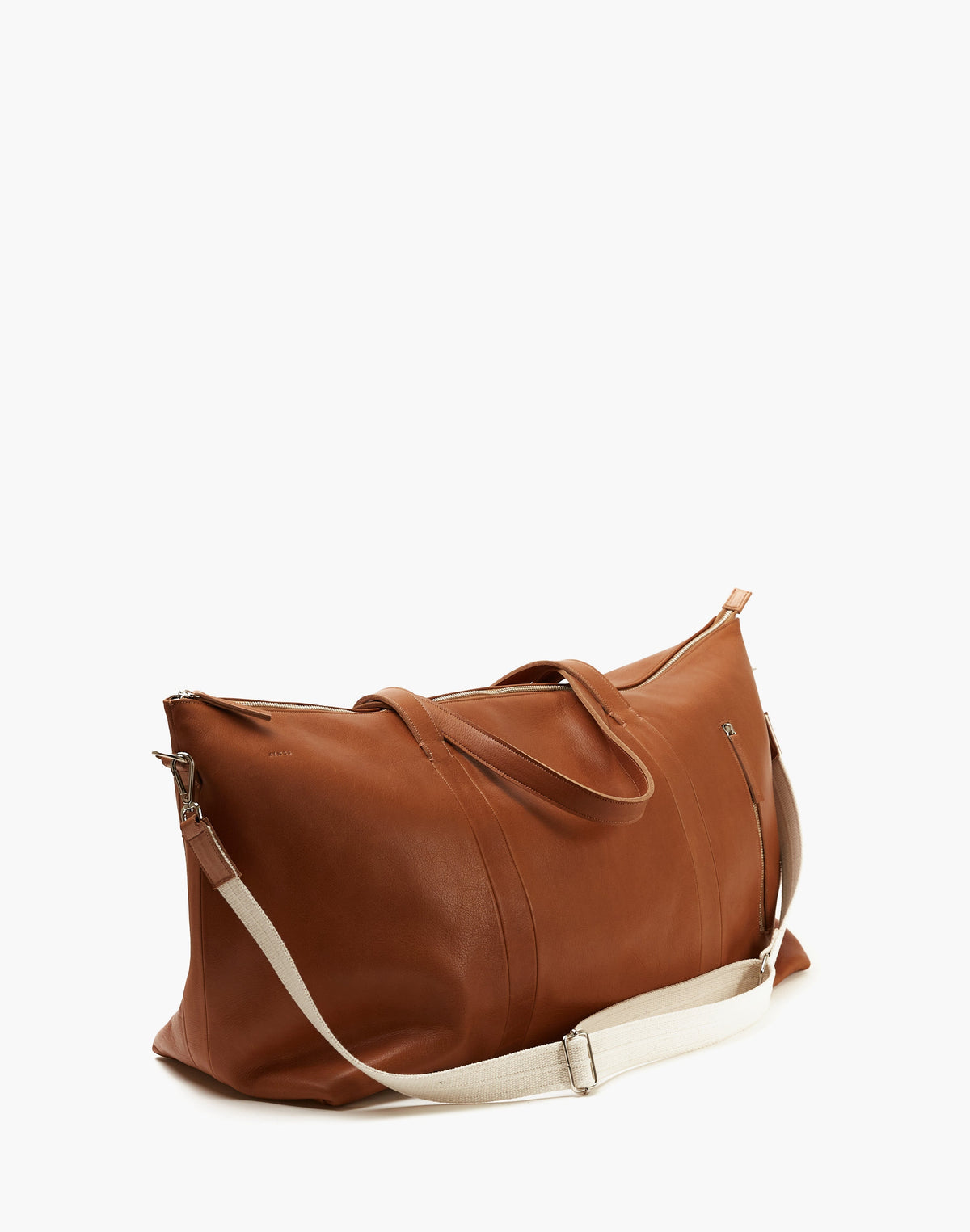 Angled view of the Malbec leather weekender in Tobacco, showing its side profile, twin handles, and cream shoulder strap.